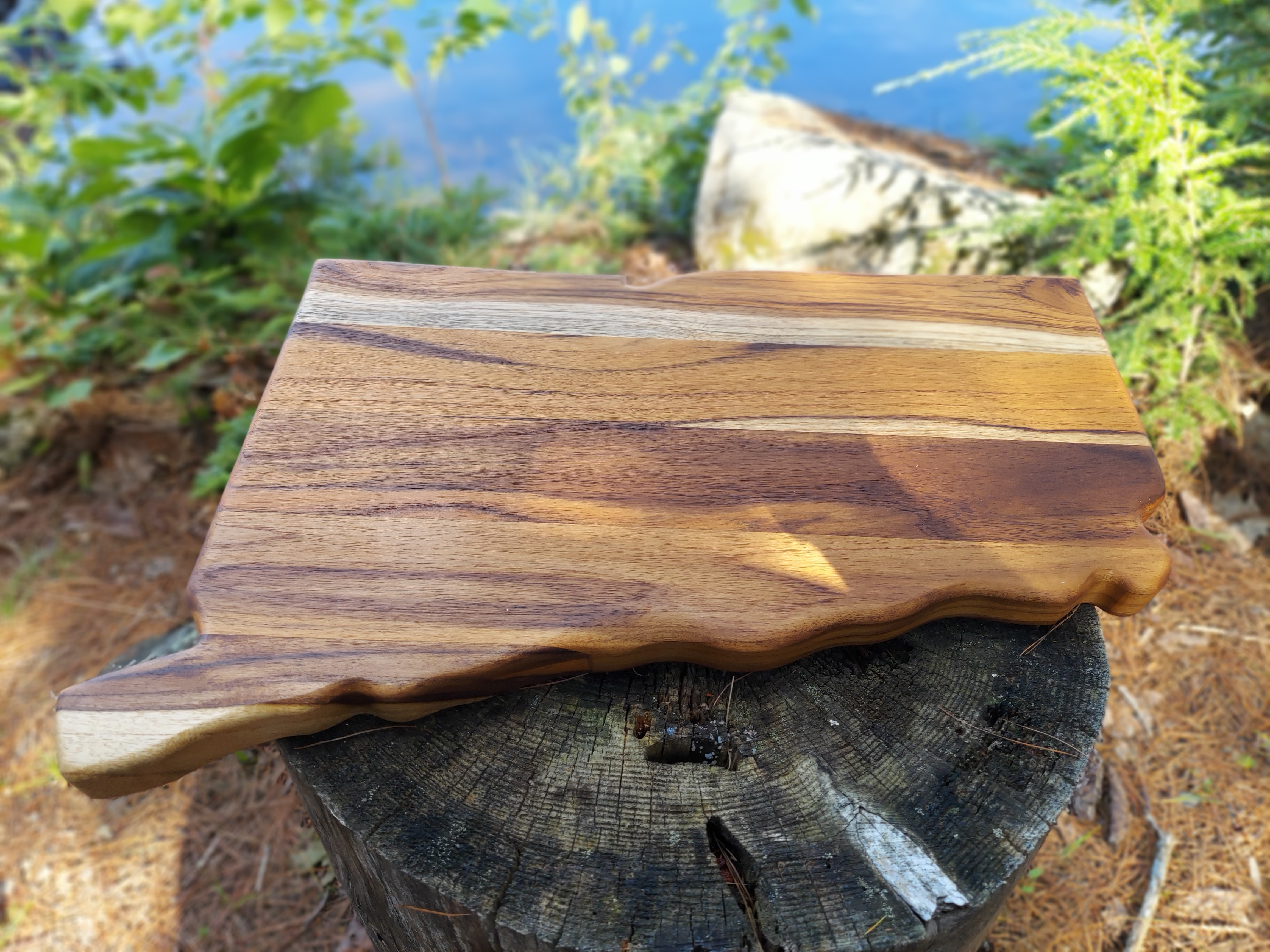 Solid teak wood charcuterie board in the shape of Connecticut with natural wood grain and no engraving.