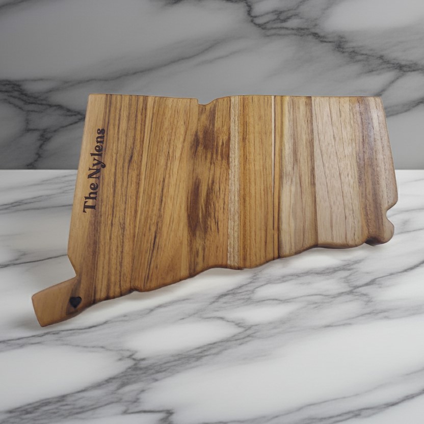 Custom Connecticut state-shaped teak wood charcuterie board with vertical "The Nylens" family name engraving.