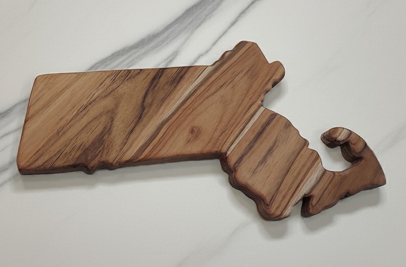 Blank Massachusetts state-shaped teak wood charcuterie board highlighting high-contrast natural wavy wood grain.