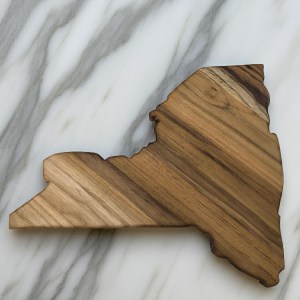 Blank New York state-shaped teak wood charcuterie board with a dramatic natural light and dark striped wood grain.