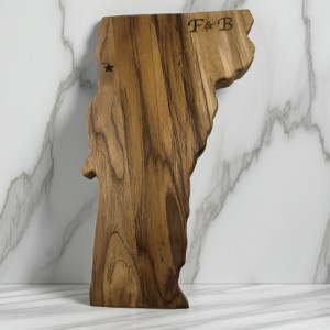 Custom Vermont state-shaped teak wood charcuterie board with "F & B" monogram and laser-engraved star on a unique marbled wood grain.